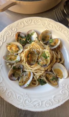 a white plate topped with pasta and clams