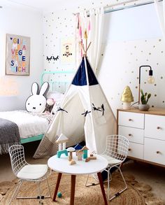 a child's bedroom with a teepee tent and two chairs