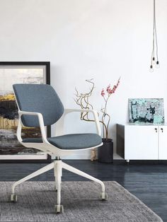 an office chair sitting on top of a rug in front of a wall with a painting