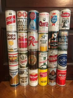 a bunch of beer cans stacked on top of each other in front of a wooden table