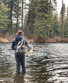 a person standing in the water holding a tennis racquet and wearing a backpack