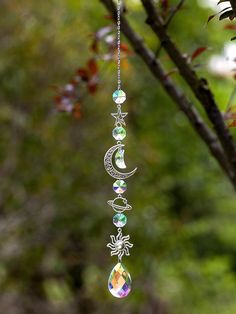 a wind chime hanging from a tree branch in the sun and moon with crystal beads