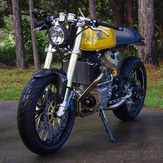 a yellow and blue motorcycle parked on the side of a road in front of some trees