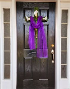 a purple door with a cross on it and flowers tied to the front door handle