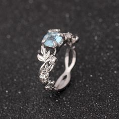 a close up of a ring on a black surface with diamonds and blue topaz