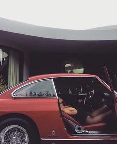 a red car parked in front of a house with its door open and the driver's seat up