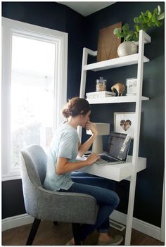 a woman sitting at a desk in front of a window with a laptop computer on it