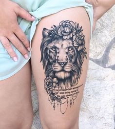 a woman's thigh with a lion and flowers tattoo on the side of her leg