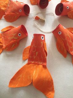 several orange fish made out of paper on top of a white table with wires attached to them