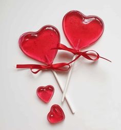 two heart shaped lollipops tied together with a red ribbon on a white background