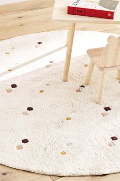 a wooden chair sitting on top of a white rug next to a table with a book