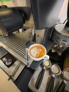 a cup of coffee sitting on top of a counter next to an espresso machine