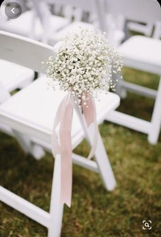 a bouquet of baby's breath sits on the back of a white folding chair