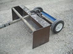 a metal cart sitting on top of gravel next to a parking lot with an empty wheel