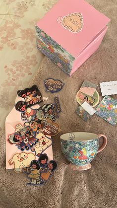 various decorative items are sitting on the floor next to a box and cup with stickers