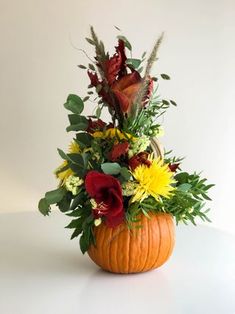 a pumpkin filled with lots of flowers on top of a table