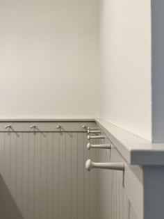 there is a row of coat hooks on the wall in this room with white walls