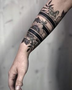 a person with a tattoo on their arm is holding onto a black and white wristband