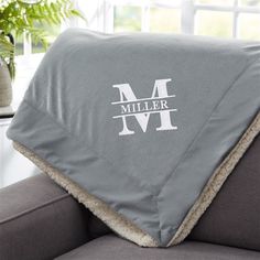 a gray couch with a blanket that says miller on it and a plant in the background