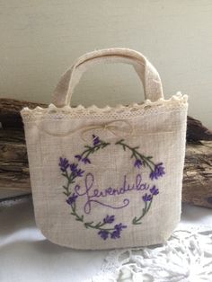 a small bag with embroidered words and flowers on it sitting on a table next to a piece of driftwood