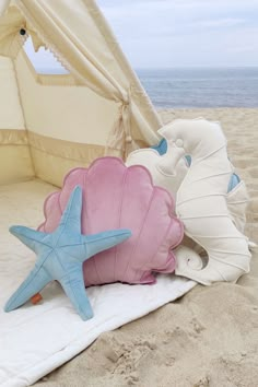 three seashells and starfish on a beach with a tent in the background