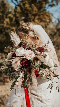 the bride is holding her bouquet with red and white flowers on it's back