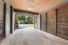 an empty room with wooden slats on the wall and doors leading to a driveway