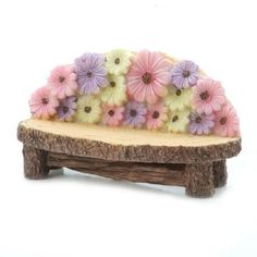 a small wooden bench with flowers on it's back end, sitting on a white background