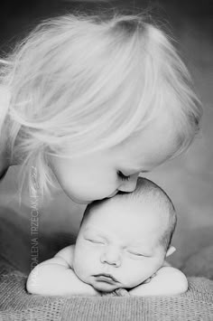 a black and white photo of a woman kissing a baby's head on her chest