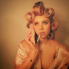 a woman with curlers on her head holding a phone to her ear and talking on the phone