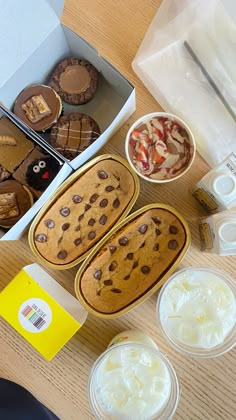 some cookies and other desserts are sitting on a wooden table with plastic containers filled with ice cream