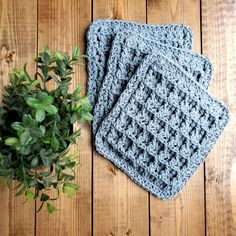 three crocheted coasters sitting on top of a wooden table next to a potted plant