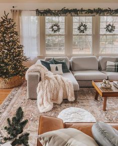 a living room filled with furniture and a christmas tree in front of a window covered in wreaths