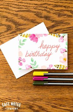 a birthday card sitting on top of a wooden table next to pencils and markers