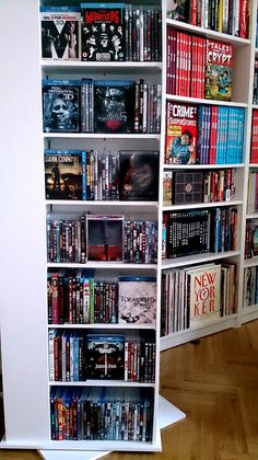 a white bookcase filled with lots of books on top of a hard wood floor