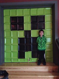 a young boy standing in front of a green door with chocolate bars on it's side