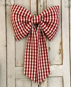 a red and white gingham bow hanging on the side of a wooden door