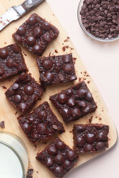 chocolate brownies cut into squares on a cutting board with a bowl of chocolate chips next to it