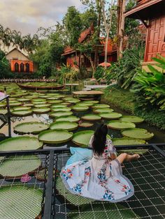 a woman sitting on the ground in front of lily pads