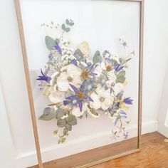 a bouquet of flowers sitting in front of a mirror on the floor next to a wall