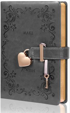 an open book with a heart on the cover and a key hanging from it's side