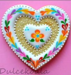 a decorated heart shaped cookie on a pink background