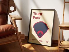 a chair and a framed poster on the floor in front of a wall that says trust park