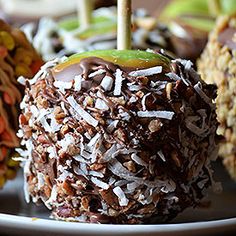 an apple covered in chocolate and sprinkles sits on a plate next to other desserts