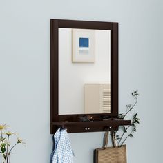 there is a mirror on the wall with a towel hanging from it and a bag next to it