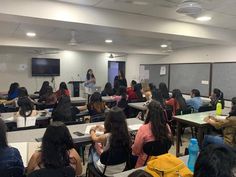 a group of people sitting at desks in front of a class room full of students