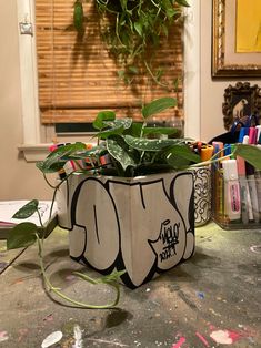 a potted plant sitting on top of a table next to a wall with graffiti