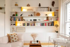 a living room filled with white furniture and lots of bookshelves on the wall