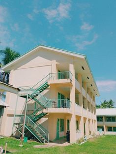 an apartment building with two balconies and green stairs leading up to the second floor