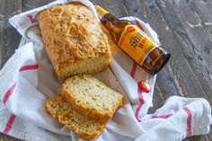 two loaves of bread on a towel next to a bottle of beer and a napkin